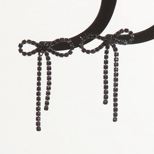 Detailed view of black rhinestone bow earrings with long shimmering tassel chains