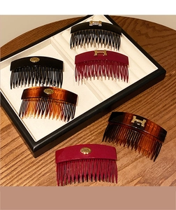 Detail view of acrylic hair combs with golden H-shaped metal buckle and round brand tags