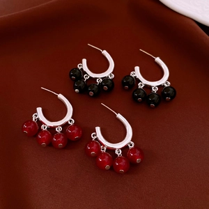 Close-up of vintage silver C-shaped earrings with red and black glass bead pendants