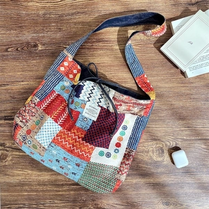Detail of colorful patchwork canvas crossbody bag with drawstring on wooden desk