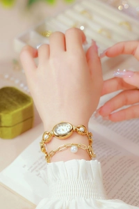 Elegant gold ladies watch with pearl bracelet set worn on a model's wrist detail