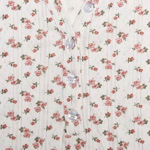 Détail du tissu en maille florale avec textures verticales et quatre boutons sur une robe