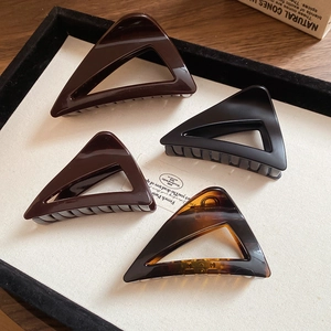 Close-up of four geometric triangle hair claws in matte black and glossy amber finishes