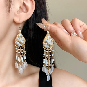 Detail showing bohemian tassel earrings with white enamel and golden bead fringe