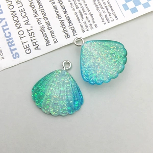 Macro shot of seashell-shaped resin charms with rainbow glitter and silver rings