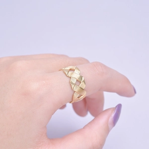Close-up detail of golden woven cross pattern and hollow texture on the steel ring