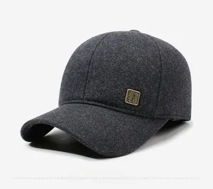 Close-up of dark grey wool baseball cap featuring a vintage bronze metal square badge
