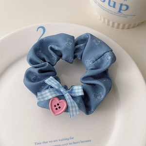 Vue détaillée d'un chouchou bleu avec motifs d'ours et bouton en forme de cœur rose