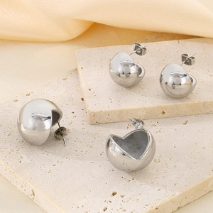 Macro detail of silver hemispherical stud earrings with a high-polish mirror finish