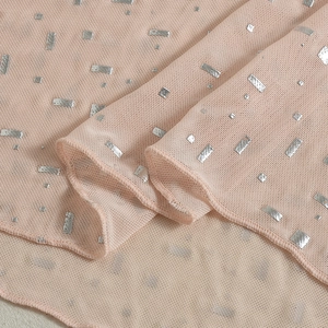 Gros plan sur un tissu en tulle rose clair avec des paillettes argentées scintillantes