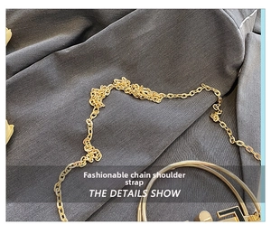Detail of elegant gold metal chain strap on dark grey blazer fabric for shoulder bag