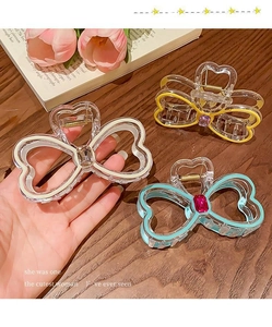 Detailed close-up of colorful resin rhinestone bow hair claws on a rustic wooden desk