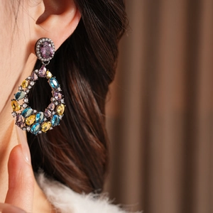 Primo piano di orecchini vintage a goccia con pietre di zircone multicolore su un modello