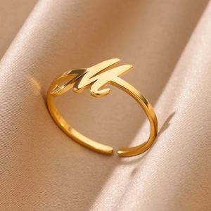 Macro view of adjustable gold ring featuring a cursive letter M on silk fabric
