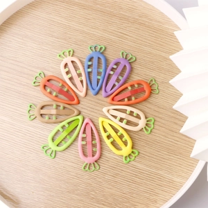 Detailed top view of ten colorful carrot-shaped plastic hair clips on a wooden tray