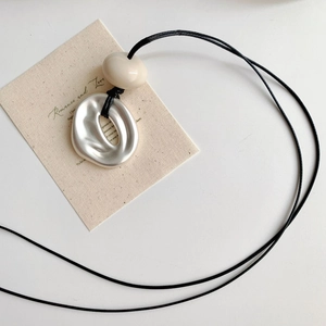 Minimalist silver irregular geometric pendant necklace with cream bead and black cord