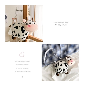 Close-up of cute plush cow crossbody bag with black and white spots and adjustable strap