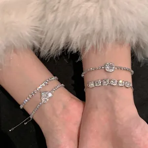 Gros plan de bracelets réglables en zircon cœur et carrés portés sur un poignet doux