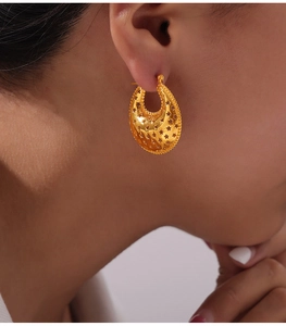 Close-up of golden hollow star earring worn by model showing metallic luster