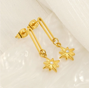 Macro detail of gold-plated star pendant earring with sparkling zircon on white background