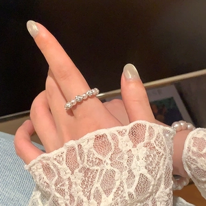 Détail d'une bague élégante en perles avec billes métalliques gravées et bracelet assorti