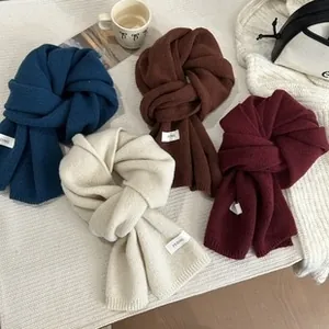 Close-up of bohemian knit scarves in navy, caramel, beige, and burgundy with letter tags