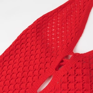 Détail de la robe en tricot rouge montrant la texture ajourée et les finitions