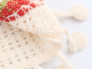 Close-up of crochet knit texture with red and olive green patterns on off-white fabric