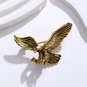 Macro shot of an antique gold eagle brooch with intricate wing texture and red rhinestone eyes