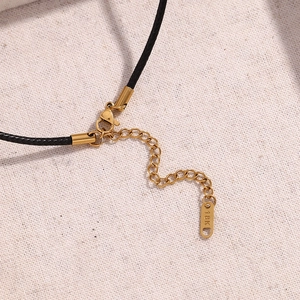 Detailed macro view of 18K gold plated clasp and adjustable chain on black cord necklace