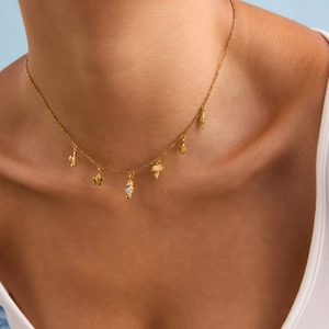 Dettaglio della collana in acciaio dorato con ciondoli tartaruga marina e palma su modella