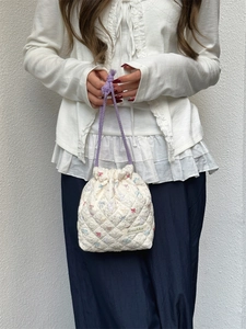 Quilted drawstring toiletry bag with floral embroidery and purple woven handles