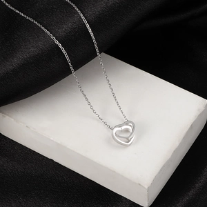 Interlocking double heart necklace in stainless steel on a luxury stone display
