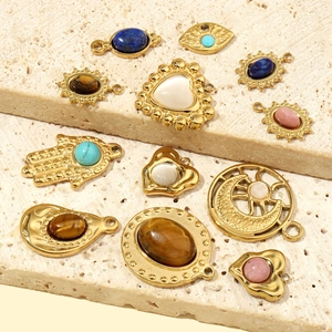 Assorted gold-plated stainless steel pendants with natural stones on a beige stone slab