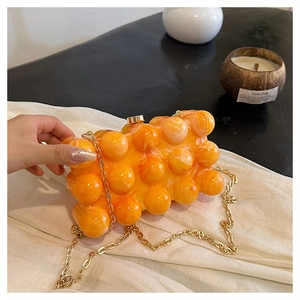 Détail de la pochette en acrylique marbré orange avec texture à bulles et chaîne