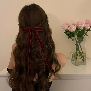Elegant deep red velvet bow hair clip with long ribbons on brunette wavy hair