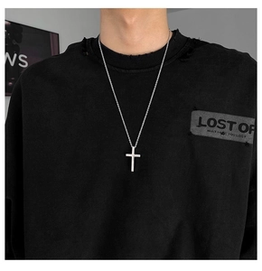 Macro view of a classic silver titanium steel cross pendant necklace on a black sweatshirt