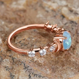Macro shot of rose gold ring with oval opal stone and crescent moon engraving