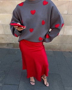 Close-up of oversized grey knit sweater with red plush hearts and red satin midi skirt
