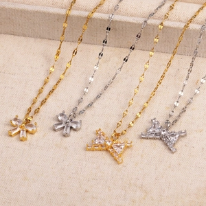 Détail de pendentifs nœuds en or et argent sertis de zircons sur des colliers à maillons