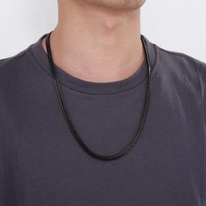Close-up of black stainless steel Franco chain necklace worn by a male model