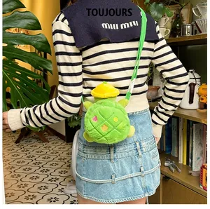 Detail of cute green plush turtle crossbody bag with yellow hat and floral embroidery