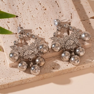 Détail macro de boucles d'oreilles argentées avec zircons et breloques boules en métal