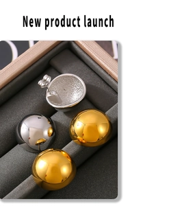 Detailed view of polished gold and silver dome stud earrings in a jewelry box