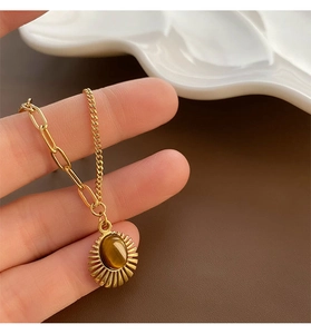 Detail of sunburst pendant with tiger eye stone on mixed paperclip and twist chain