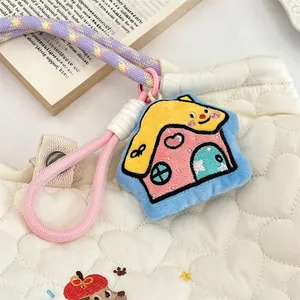 Detail of cute house plush keychain with heart embroidery on a white quilted bag