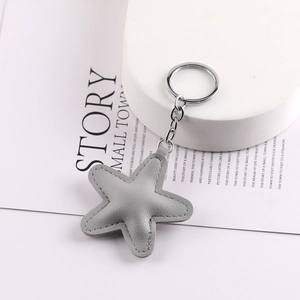 Handmade grey leather star keychain accessory with metal ring on a minimalist background