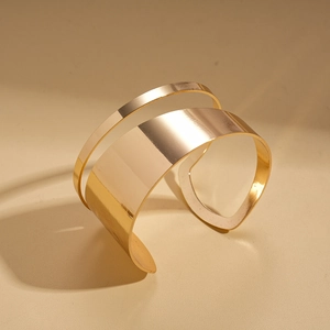 Macro shot of minimalist 18K gold plated wide open bangle with polished mirror finish