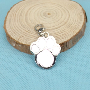 Detailed view of silver dog paw pendant with pink enamel and lobster clasp on wood