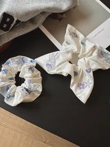 Close-up of white satin hair tie set with detailed ocean-themed sea life embroidery